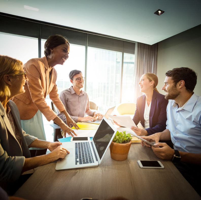 Businesswoman sharing her presentation with attentive colleagues in a well-lit meeting room, fostering collaboration and discussion.