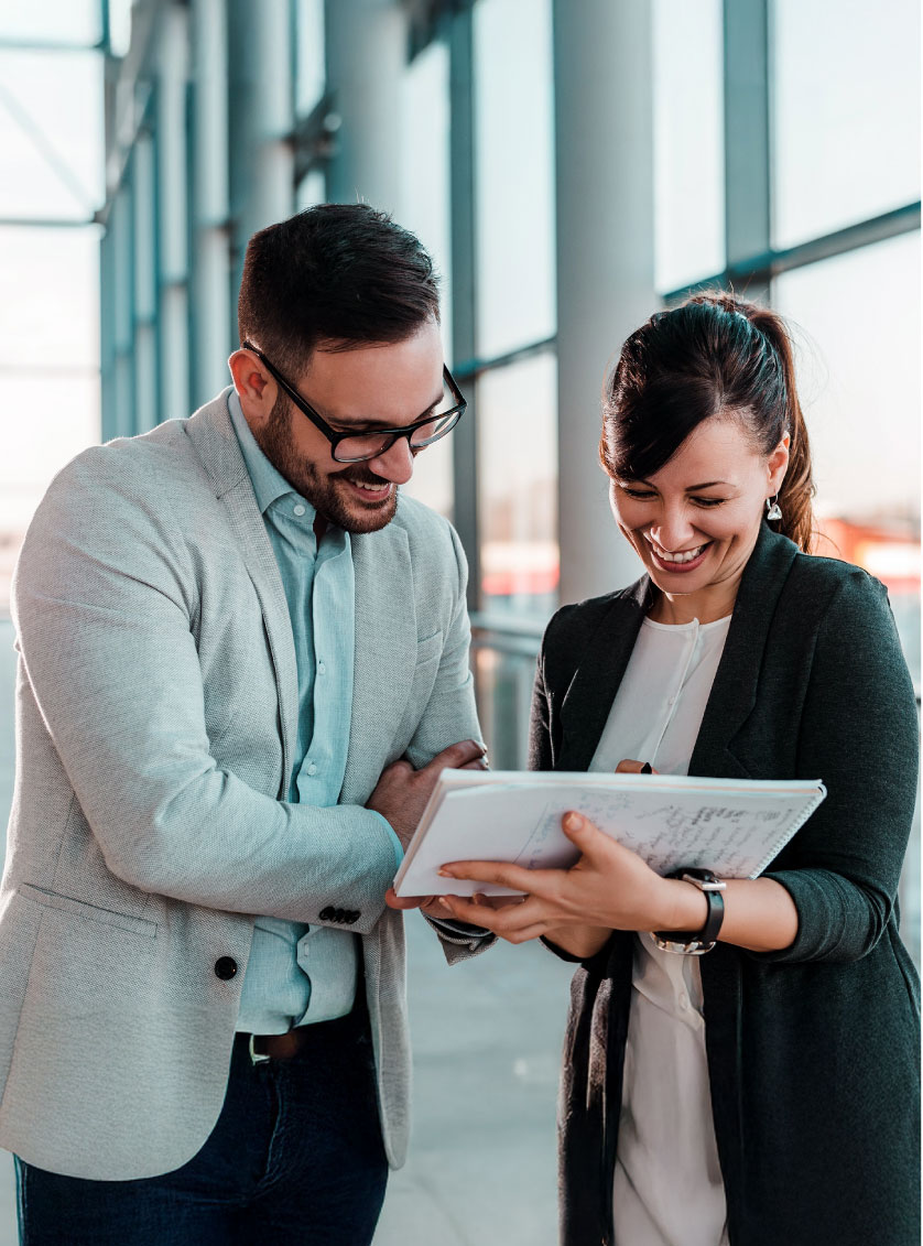 A man and woman in business engaged with a tablet, likely reviewing important information.