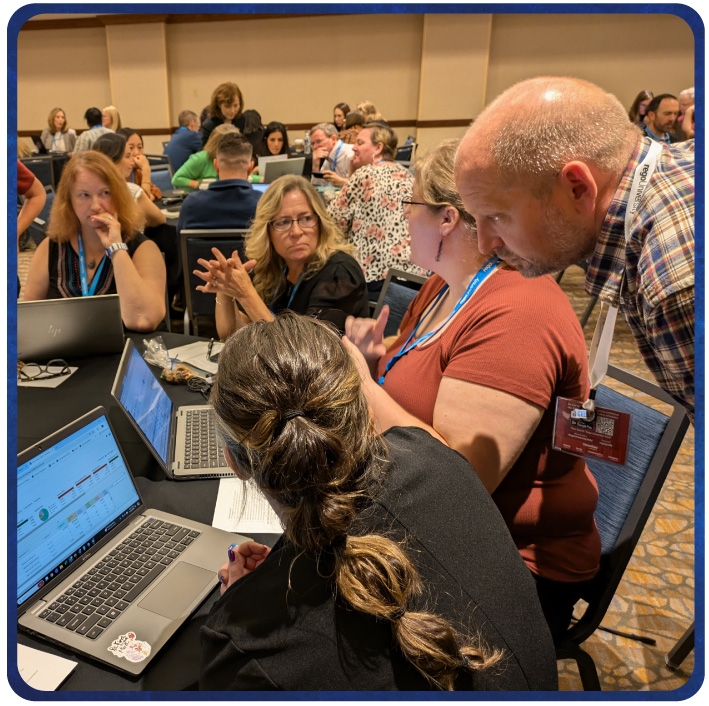 Small group collaborating on laptops during a hands-on workshop at a professional conference. 