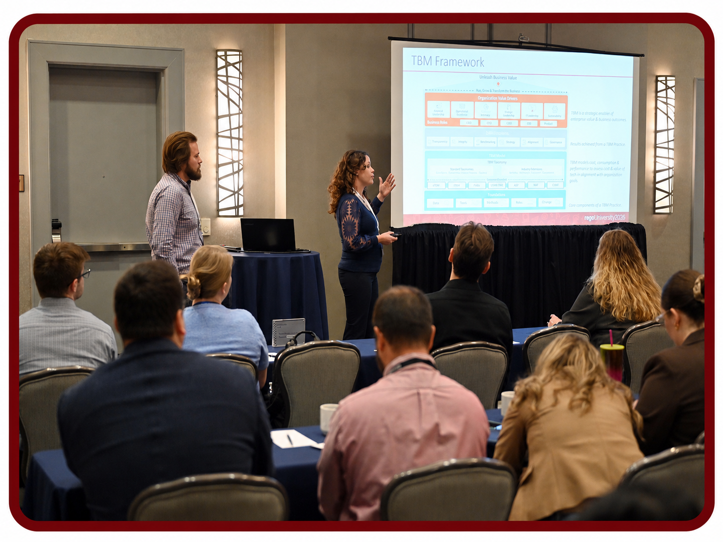 Presenter leads a Rego University session on IBM Apptio framework while attendees watch and take notes.